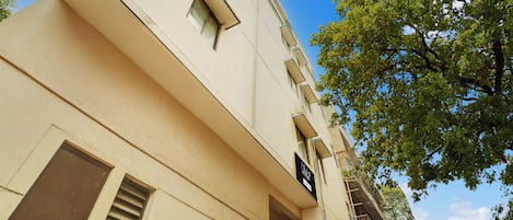 Un edificio con fachada color beige, múltiples ventanas y una señal visible.