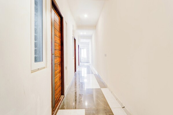 A corridor with a wooden door and a window on the left, leading to a room. - Super Collection O RS Puram North (Coimbatore)