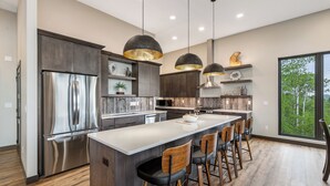 Een moderne keuken met een centraal eiland, barkrukken en hanglampen.