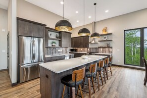 A modern kitchen with a central island, bar stools, and pendant lighting. - New Hilltop Escape, Sweeping Black Hills Views w/ Hot Tub, Large Driveway (Lead)