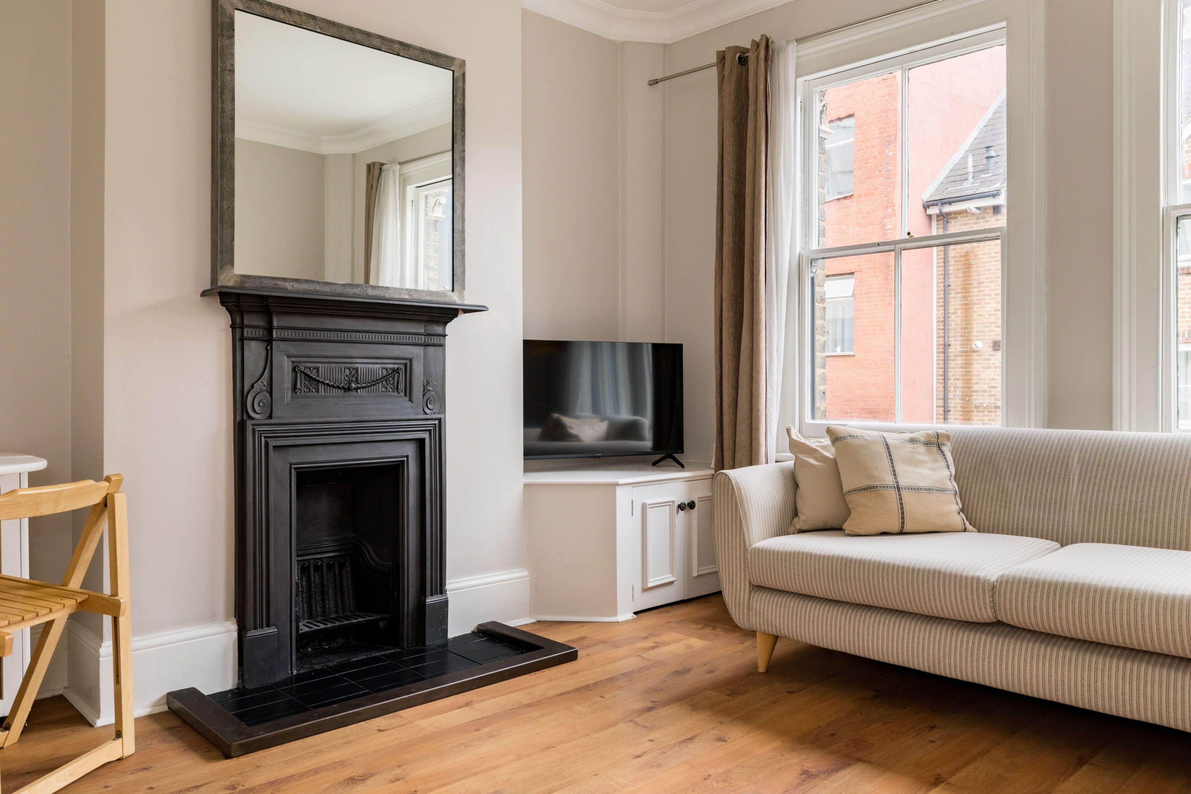 A living room with a fireplace, a television, a sofa, and a window with curtains.