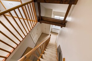 A wooden staircase with a handrail leading to a landing. - Brick & Beam on Tabard (London)