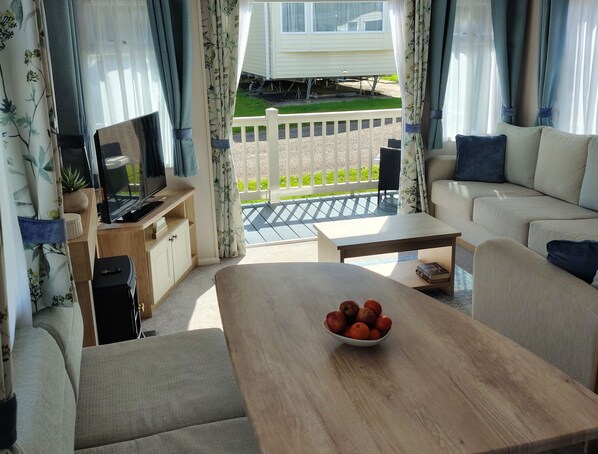 A cozy living area with a sofa, a coffee table, and a TV on a stand. - Beverley Bay (Paignton)