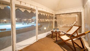 A tent with a view of an outdoor area, including a pool and lounge chairs. - The Hukum Desert Camp (Jaisalmer)