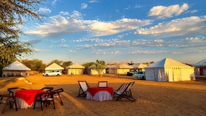 A desert camp with tents, tables, and chairs set up for outdoor dining. - The Hukum Desert Camp (Jaisalmer)