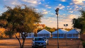 A desert landscape with tents and a car, suggesting a temporary accommodation setup. - The Hukum Desert Camp (Jaisalmer)