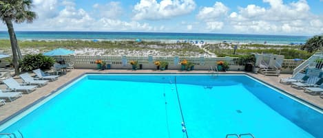 A clear blue swimming pool with a view of the beach and ocean.