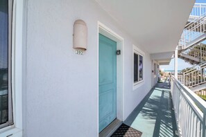 Ein Gebäude mit einer hellblauen Tür, einem Hausnummernschild und einem Balkon mit Geländern.