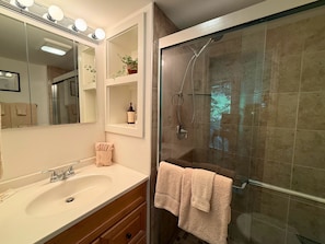 A bathroom with a sink, mirror, and shower. - one of a-kind slopeside condo, located just across the street from SM Skiing (Sugar Mountain)