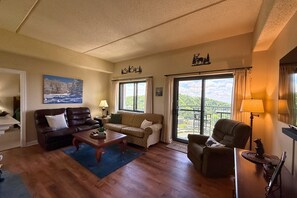 A living room with a sofa, armchair, coffee table, and a painting on the wall. - Escape to the beauty of Sugar Mountain in this comfortable 2-bedroom condo (Sugar Mountain)