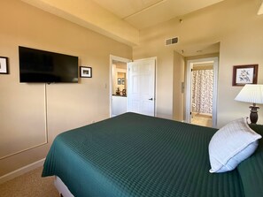 A bedroom with a bed, a television mounted on the wall, and a door leading to another room. - Escape to the beauty of Sugar Mountain in this comfortable 2-bedroom condo (Sugar Mountain)
