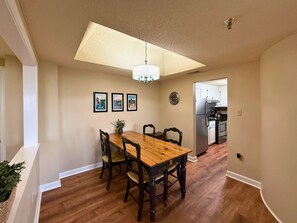 A dining area with a wooden table and chairs, a chandelier, and a kitchen in the background. - Escape to the beauty of Sugar Mountain in this comfortable 2-bedroom condo (Sugar Mountain)