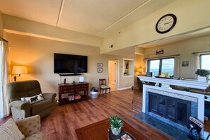 A living room with a fireplace, a television, and a dining area with a view. - Escape to the beauty of Sugar Mountain in this comfortable 2-bedroom condo (Sugar Mountain)