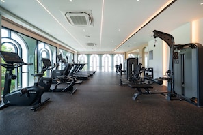 Un gimnasio con cintas de correr, elípticas y equipo de pesas.