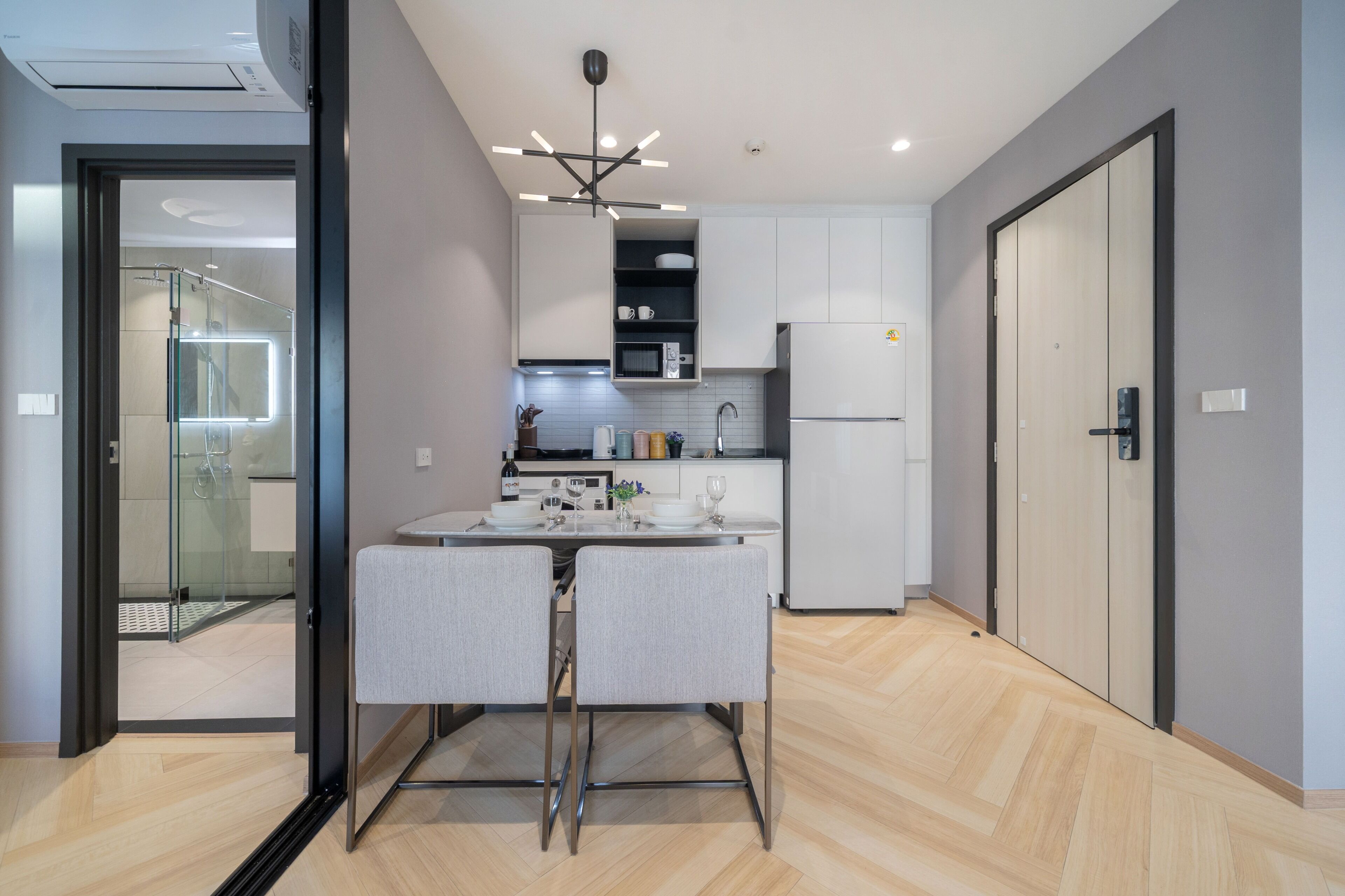 Una cocina moderna con microondas incorporado, refrigerador y comedor con mesa y sillas.
