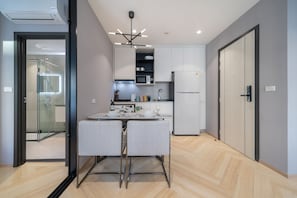 Una cocina moderna con microondas incorporado, refrigerador y comedor con mesa y sillas.