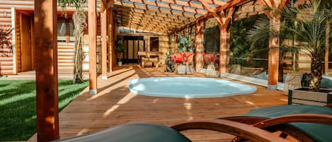 A wooden deck with a hot tub, lounge chairs, and a pergola structure.