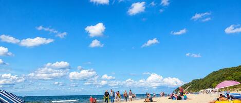 Una playa con gente, sombrillas y cielo despejado.