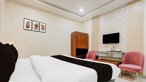 Habitación de hotel con cama, escritorio, silla, armario y televisor de pantalla plana montado en la pared.