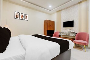 Habitación de hotel con cama, escritorio, silla, armario y televisor de pantalla plana montado en la pared.