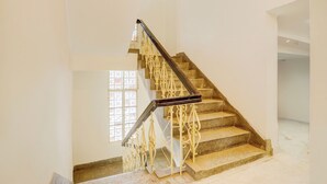 Una escalera con barandilla metálica y una ventana con celosía decorativa.