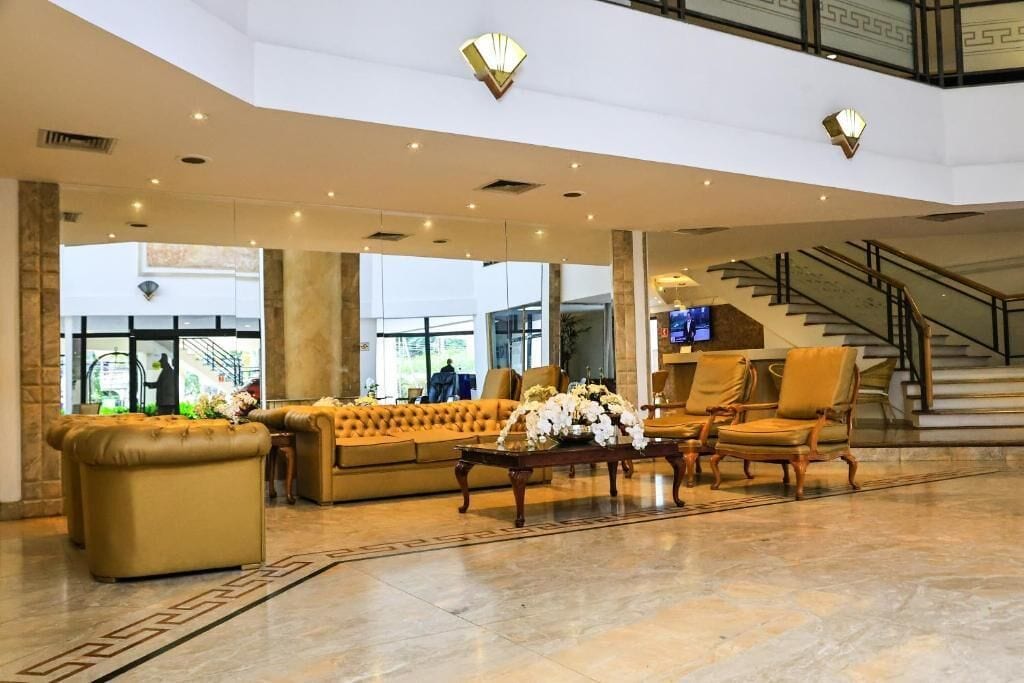 Eine großzügige Lobby mit einer Couch, Sesseln, einem Couchtisch und einer Treppe.