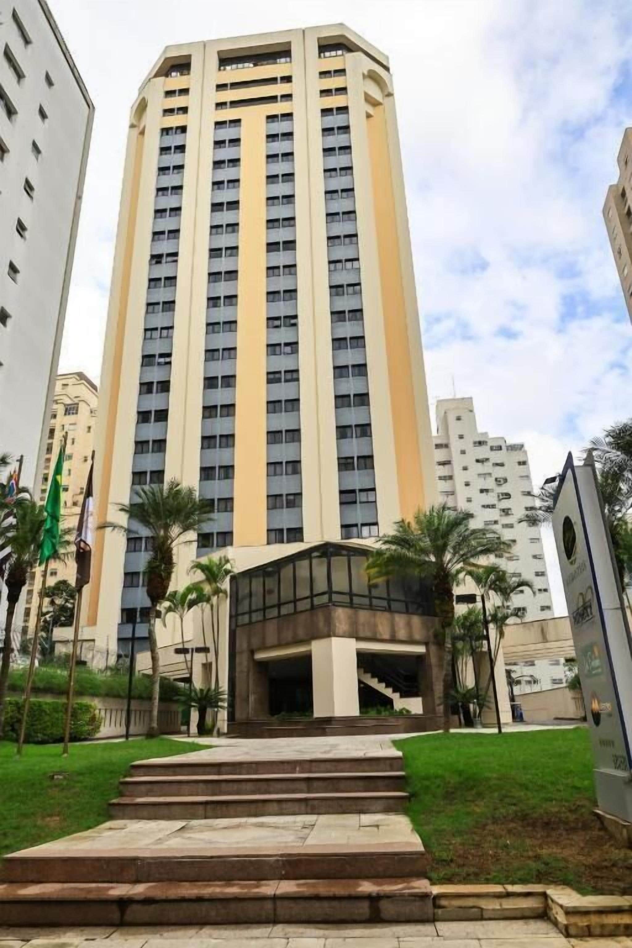 Un alto edificio residenziale con un ingresso centrale e una scala che vi conduce.