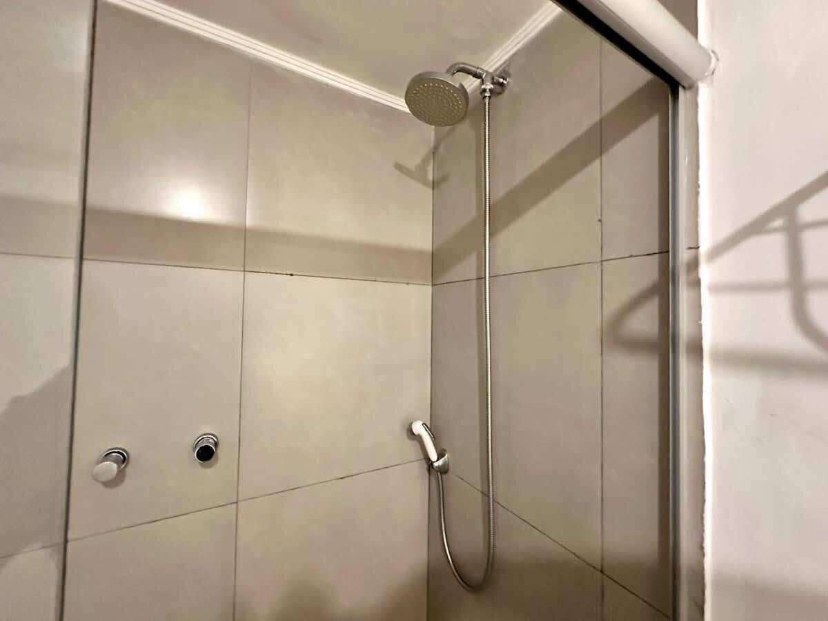 Une douche équipée d’un pommeau de douche à main et d’un robinet fixé au mur.
