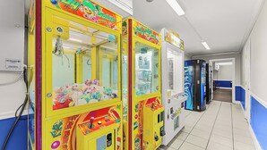Een hal met kleurrijke grijpmachines en een zichtbare stopcontact op de muur.