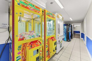 A hallway with colorful claw machines and a visible electrical outlet on the wall. - NEW! Wet Bar, Beachfront, Fully Renovated, 3 Pools, Hot Tub, Gym (Panama City Beach)