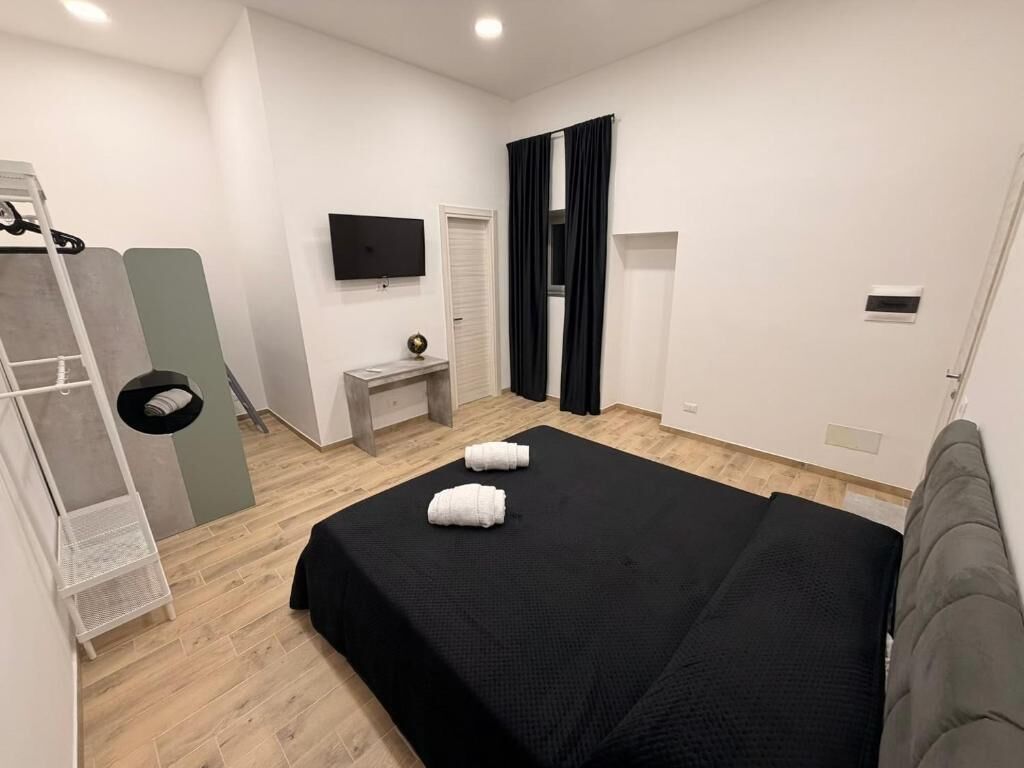 Een hotelkamer met een bed, een televisie, een klein tafeltje en een kledingkast.