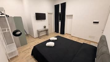 Een hotelkamer met een bed, een televisie, een klein tafeltje en een kledingkast.