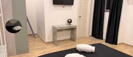 A hotel room with a bed, a desk, a television, and a wardrobe.