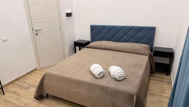 A bedroom with a bed, two nightstands, a door, and a blue headboard.