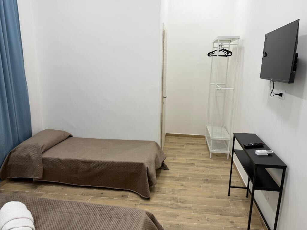 Une petite pièce, bien rangée, comprenant un lit, une table de chevet, un téléviseur et une armoire.