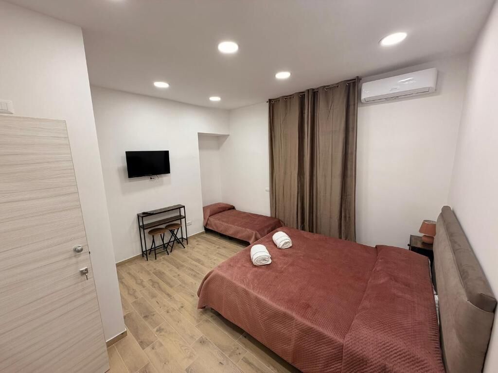 Un dormitorio con dos camas, un escritorio, un televisor y un equipo de aire acondicionado.