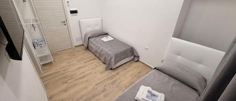 Una habitación compacta con dos camas, un armario y una mesita de noche.