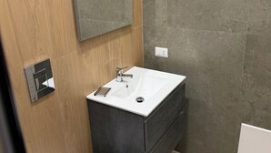 A modern bathroom with a wooden vanity, a white sink, and a mirror.