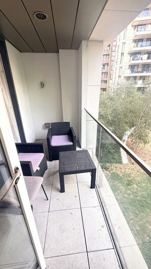 A balcony with a chair, a small table, and a view of a residential area. - Apartment Sleeps 6 With Balcony (London)