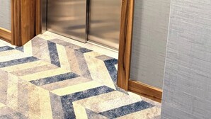 Een hotelefter met een houten frame, een metalen binnenkant en een bedieningspaneel met een nummeraanduiding.