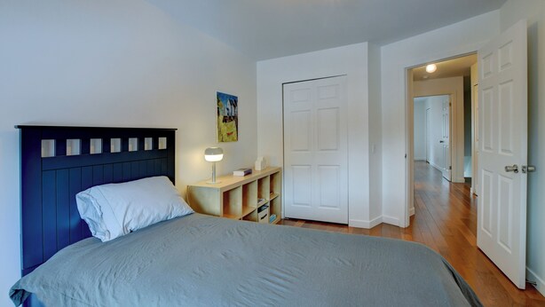 A bedroom with a bed, bedside table, lamp, and a door leading to another room. - Spacious 1,250 sq ft 2-Level 3BR Condo + Parking in Petite-Bourgogne, Montreal (Montréal)