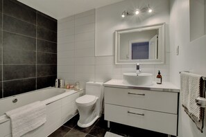 Un baño moderno con bañera, inodoro y tocador.
