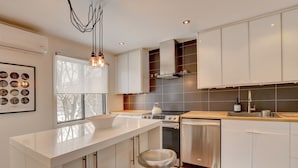 A modern kitchen with a central island, stainless steel appliances, and a view of the outdoors. - Spacious 1,250 sq ft 2-Level 3BR Condo + Parking in Petite-Bourgogne, Montreal (Montréal)