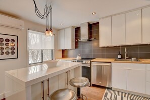 A modern kitchen with a central island, stainless steel appliances, and a view of the outdoors.