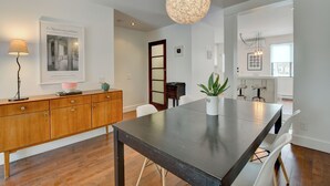 A modern kitchen with a large island, pendant lighting, and a dining area with a table and chairs. - Spacious 1,250 sq ft 2-Level 3BR Condo + Parking in Petite-Bourgogne, Montreal (Montréal)