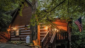 Une cabane en bois avec un porche, un escalier et un drapeau américain.