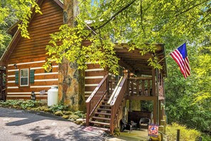 A wooden cabin with a porch, a flag, and a welcome mat. - New Listing Hot Tub, Pool Table, Free Attractions (Sevierville)