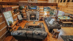 Un intérieur de chalet chaleureux avec une cheminée en pierre, des meubles en bois et un coin repas.