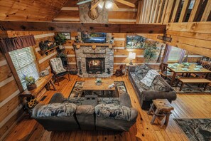A cozy cabin interior with a stone fireplace, wooden furniture, and a dining area. - New Listing Hot Tub, Pool Table, Free Attractions (Sevierville)