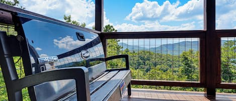 Una terraza de madera con un banco que da a un paisaje montañoso.